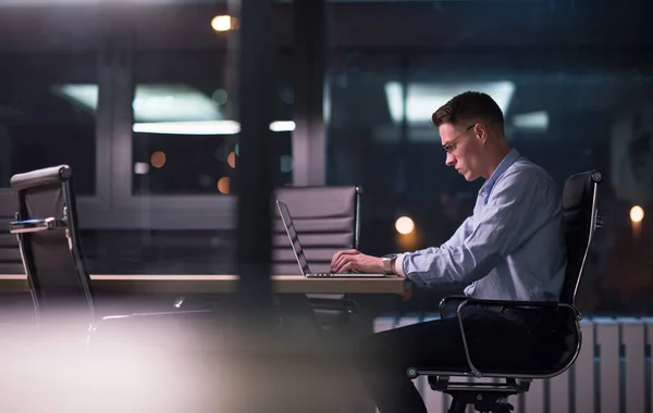 Uomo che lavora su computer portatile in ufficio scuro — Foto Stock