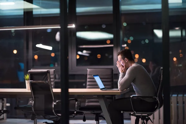 Uomo che lavora su computer portatile in ufficio scuro — Foto Stock