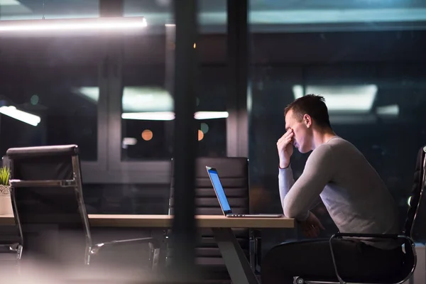 Человек работает на ноутбуке в темном офисе — стоковое фото