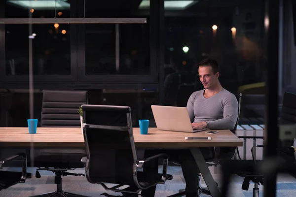 Чоловік працює на ноутбуці в темному офісі — стокове фото