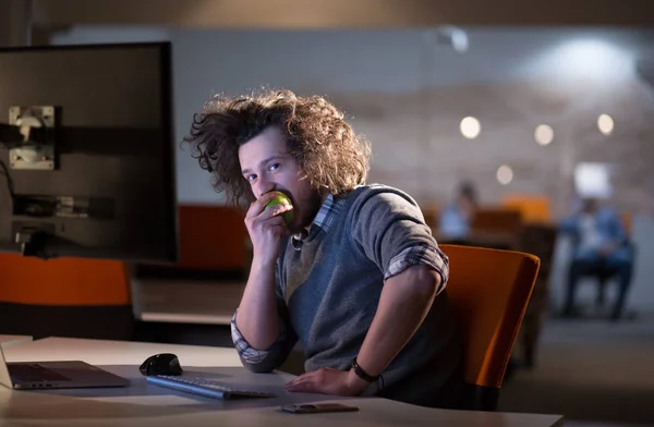 Человек ест яблоко в своем кабинете — стоковое фото