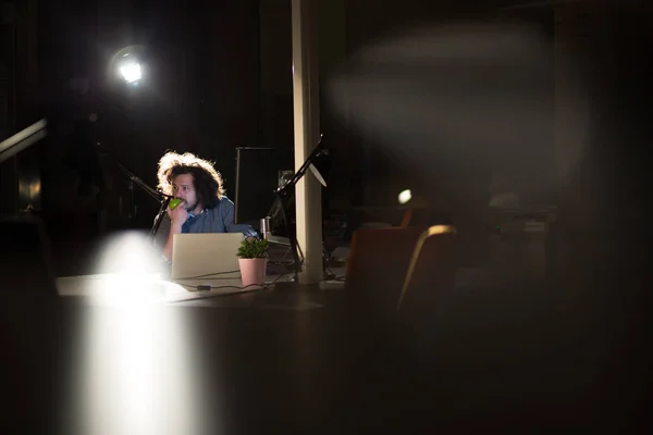 Человек, работающий за компьютером в темном офисе — стоковое фото