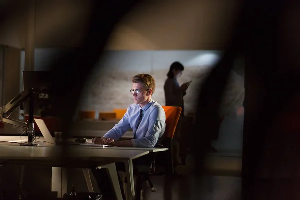 Людина працює на комп'ютері в темному офісі — стокове фото