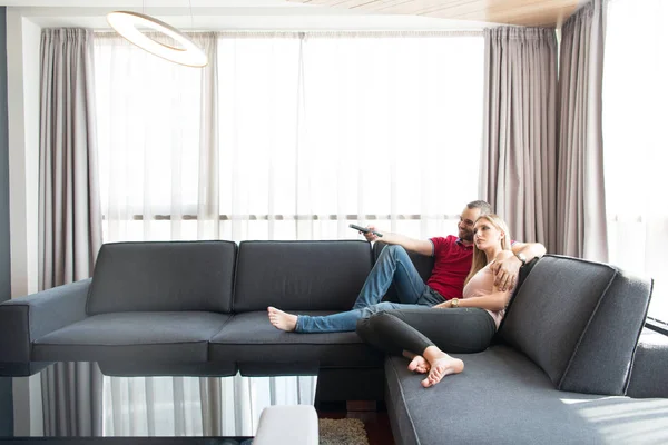 Pareja joven en el sofá viendo la televisión — Foto de Stock