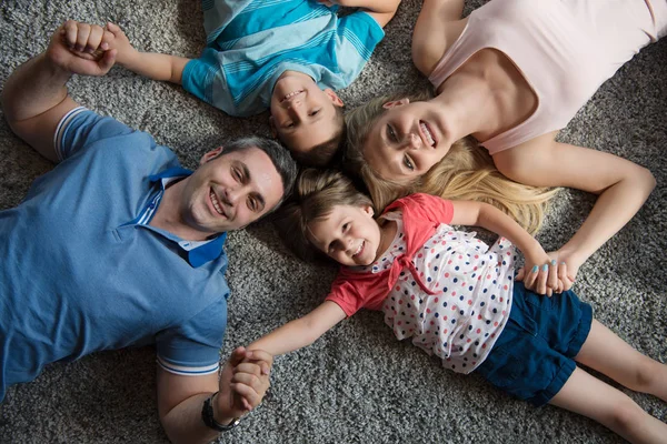 Família feliz deitada no chão — Fotografia de Stock