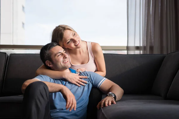 Jovem casal bonito abraçando no sofá — Fotografia de Stock