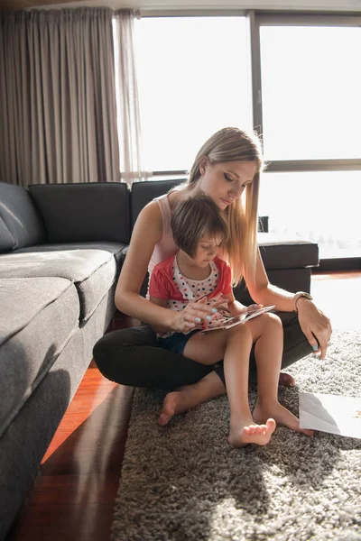 Мати і її маленька дочка використовують планшет на підлозі — стокове фото