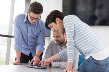 Bir sonraki toplantıya hazırlanan ve dijital tablet kullanarak fikirleri tartışan iş adamları grubu.