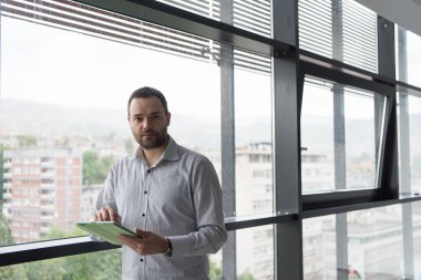 İşadamı kullanarak Tablet içinde ofis binası pencere tarafından