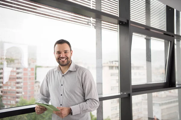 Empresario usando tableta en edificio de oficinas por ventana — Foto de Stock