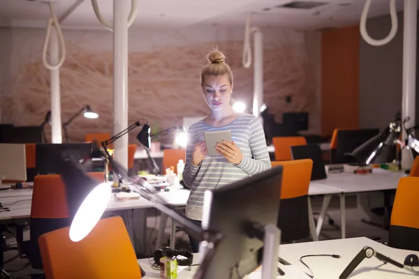 Женщина работает на цифровой планшет в ночном офисе — стоковое фото