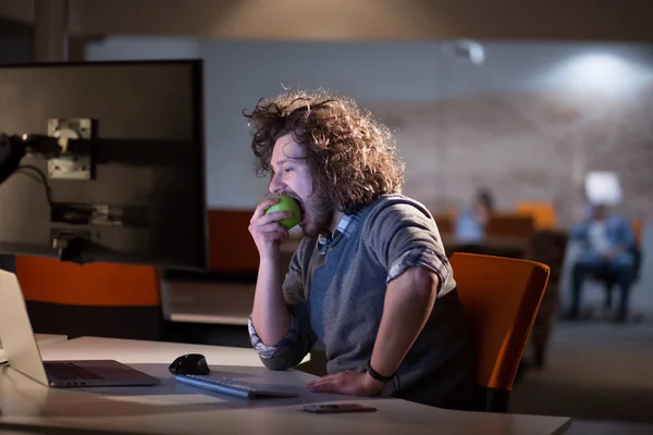 Homme mangeant de la pomme dans son bureau — Photo