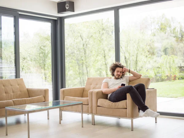 Jonge man met behulp van een mobiele telefoon thuis — Stockfoto