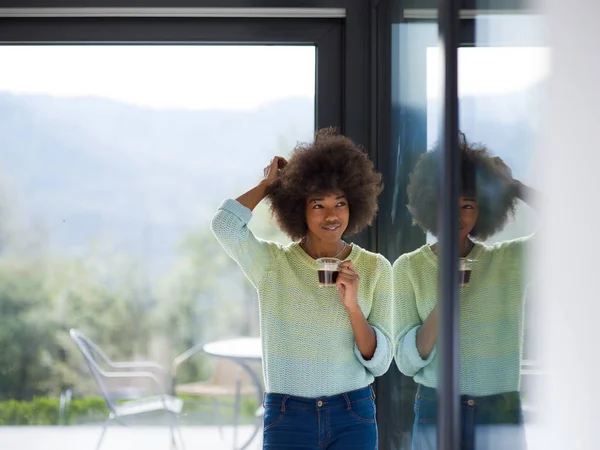 Mujer afroamericana bebiendo café mirando por la ventana —  Fotos de Stock