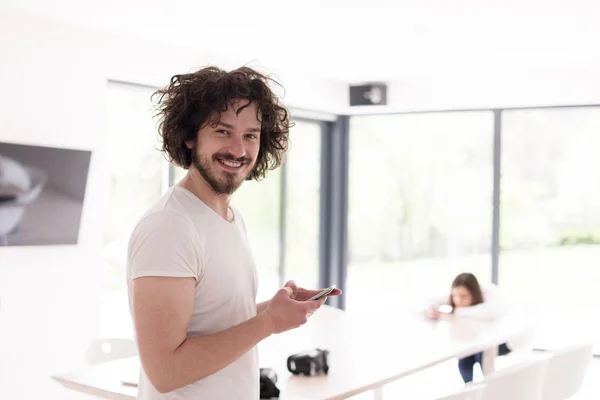 Ung man använder en mobiltelefon hemma — Stockfoto