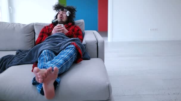 Больной человек держит чашку, сидя на диване — стоковое видео
