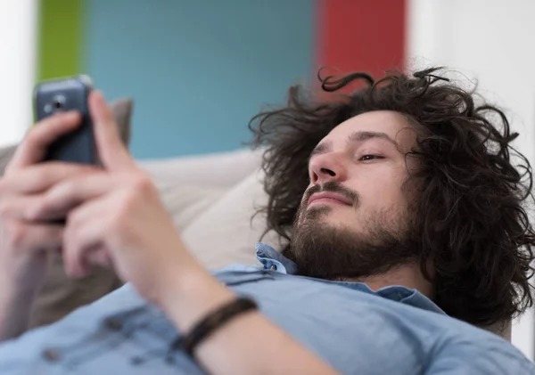 Ung man använder en mobiltelefon hemma — Stockfoto