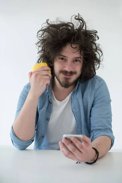 Joven comiendo manzana y usando un teléfono móvil en casa — Foto de Stock