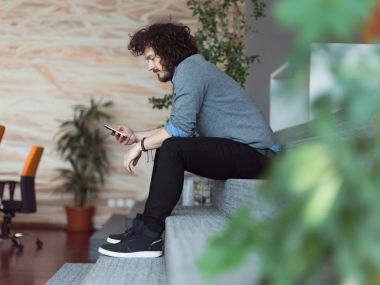 Genç casual işadamı holding smartphone