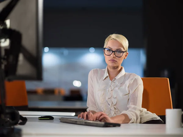 Женщина, работающая за компьютером в темном офисе — стоковое фото