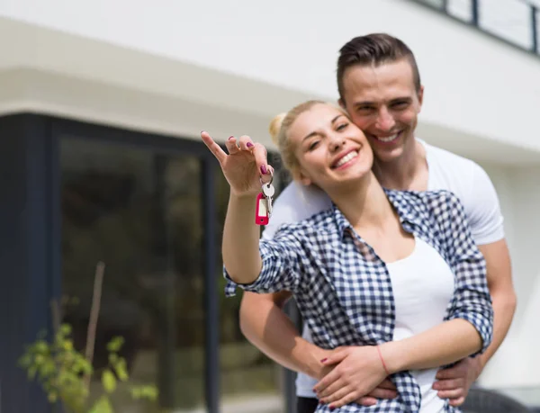 Pareja abrazándose frente a una nueva casa de lujo — Foto de Stock