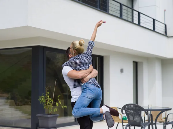 Casal abraçando na frente de nova casa de luxo — Fotografia de Stock