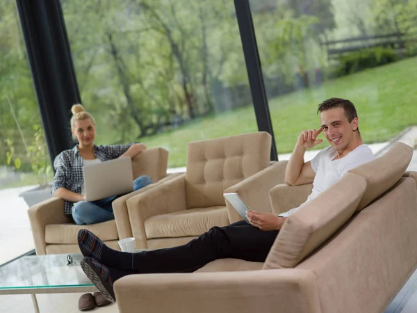 Casal relaxante em casa com computadores tablet e laptop — Fotografia de Stock