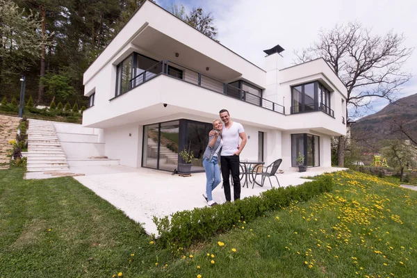 Casal abraçando na frente de nova casa de luxo — Fotografia de Stock