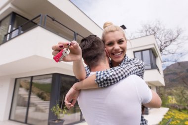 couple hugging in front of  new luxury home clipart