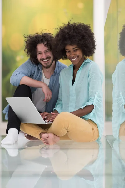 Multiethnisches Paar mit Laptop auf dem Fußboden — Stockfoto
