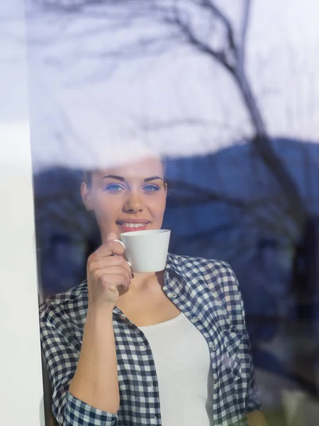 Mladá žena pít ráno kávu u okna — Stock fotografie