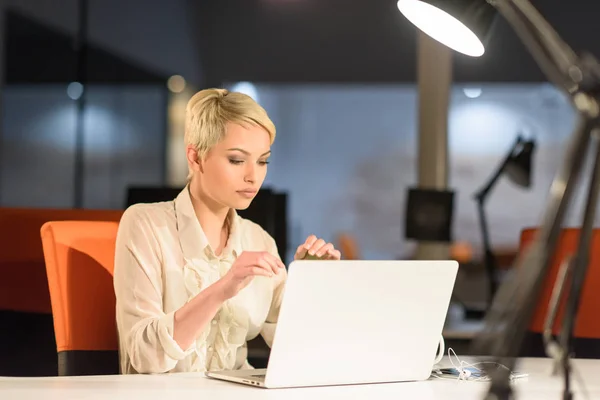 Женщина работает на ноутбуке в ночном офисе стартапа — стоковое фото