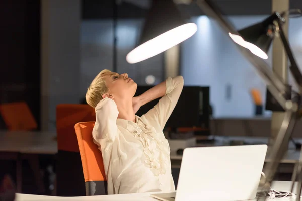Женщина работает на ноутбуке в ночном офисе стартапа — стоковое фото