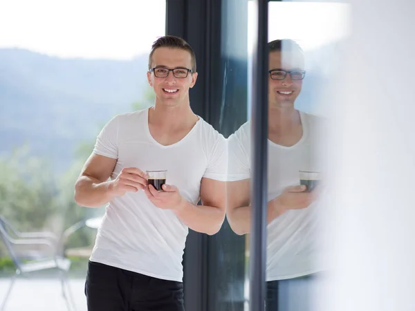 Jonge man drinken's ochtends koffie bij het raam — Stockfoto