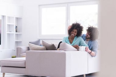 çok ırklı çift evde kanepede oturmuş kahve içme