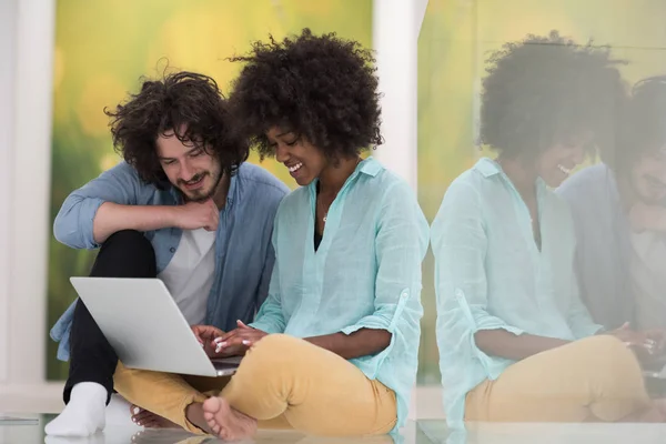 Multiethnisches Paar mit Laptop auf dem Fußboden — Stockfoto