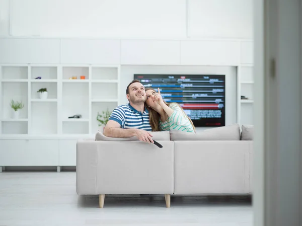 Jong (echt) paar op de bank tv-kijken — Stockfoto