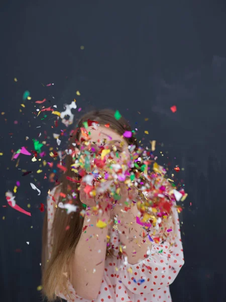 Mulher soprando confete no ar isolado sobre cinza — Fotografia de Stock