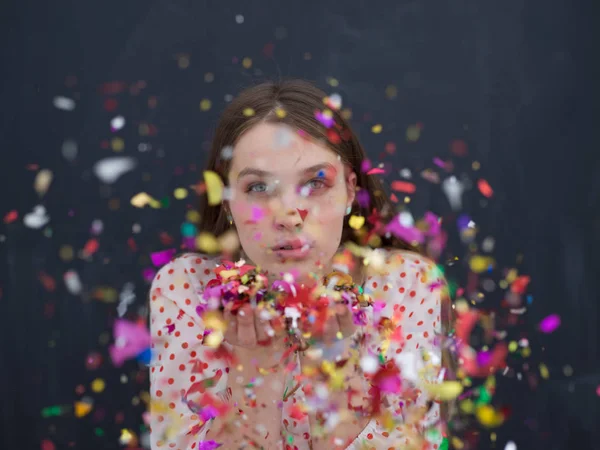 Vrouw waait confetti in de lucht geïsoleerd over grijs — Stockfoto