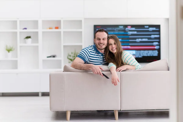 Młoda para na kanapie, oglądanie telewizji — Zdjęcie stockowe