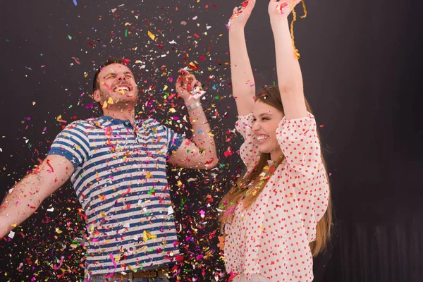 Couple soufflant confettis dans l'air isolé sur gris — Photo