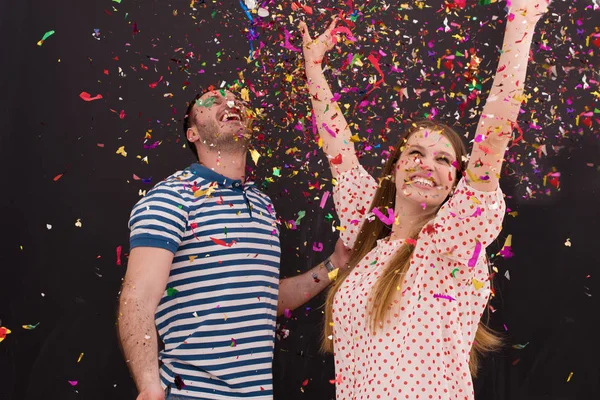 Couple blowing confetti in the air isolated over gray — Stock Photo, Image