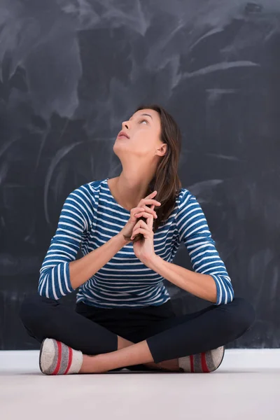 Mujer sentada frente al tablero de dibujo de tiza — Foto de Stock