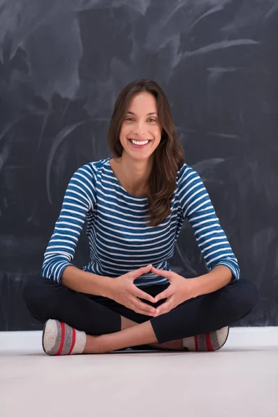 Woman sitting in front of chalk drawing board — Stock Photo, Image