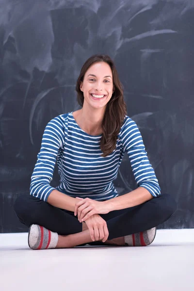 Woman sitting in front of chalk drawing board — Stock Photo, Image