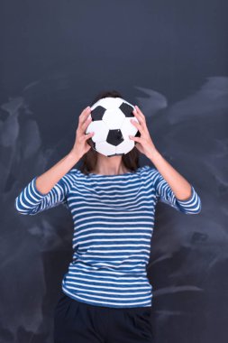 bir futbol topu tebeşir çizim kurulu önünde tutan kadın