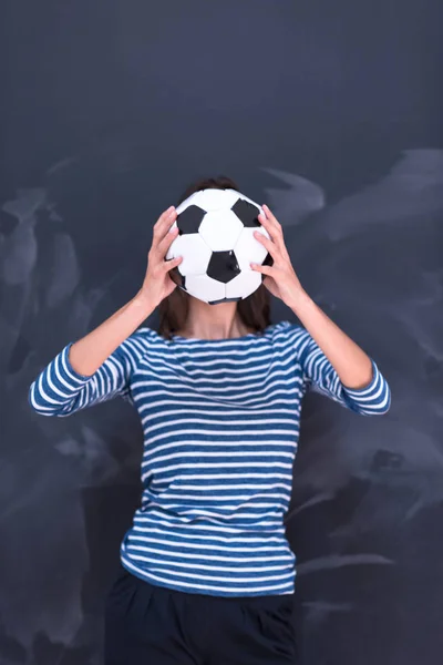 Mujer sosteniendo una pelota de fútbol delante de la pizarra de dibujo — Foto de Stock