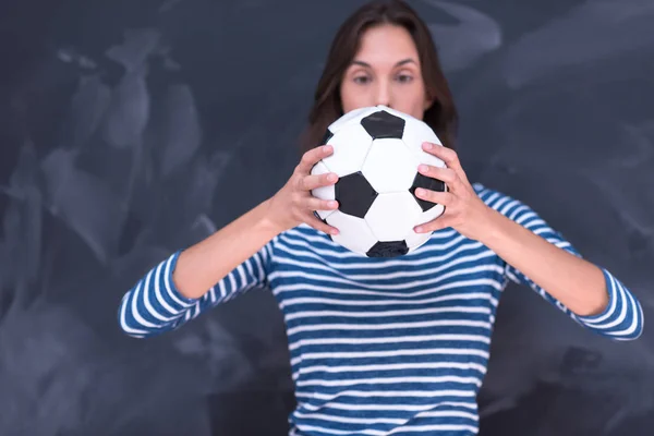 Mujer sosteniendo una pelota de fútbol delante de la pizarra de dibujo — Foto de Stock