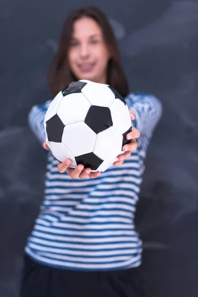 Mulher segurando uma bola de futebol na frente do quadro de desenho de giz — Fotografia de Stock