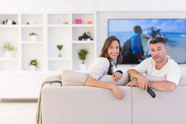 Pareja joven en el sofá viendo la televisión —  Fotos de Stock